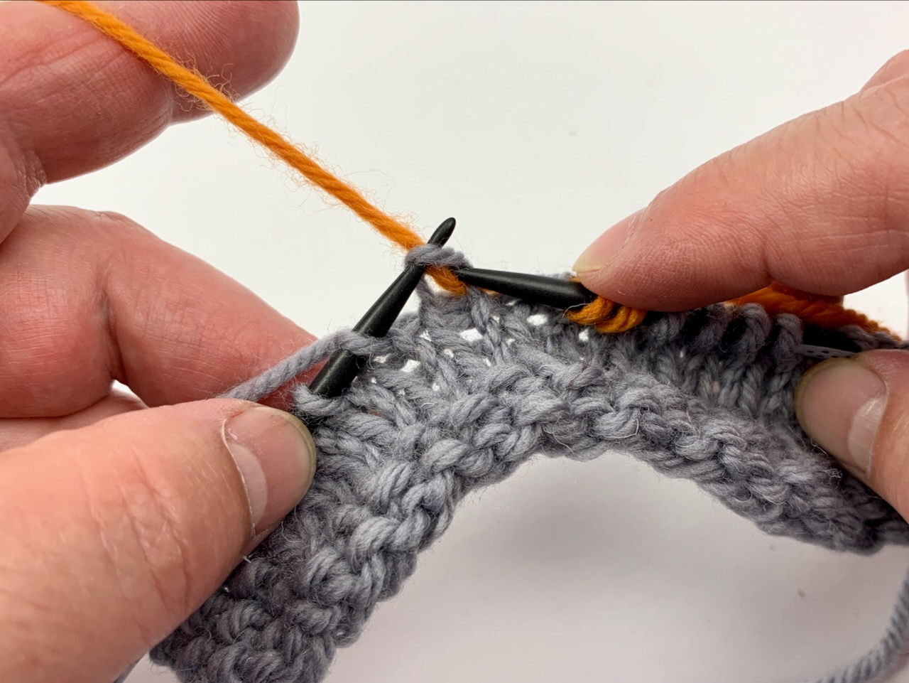 Abwechselnd werden beim Einweben von Fäden die rechte Nadelspitze einmal über, einmal unter dem einzuwebenden Faden geführt.