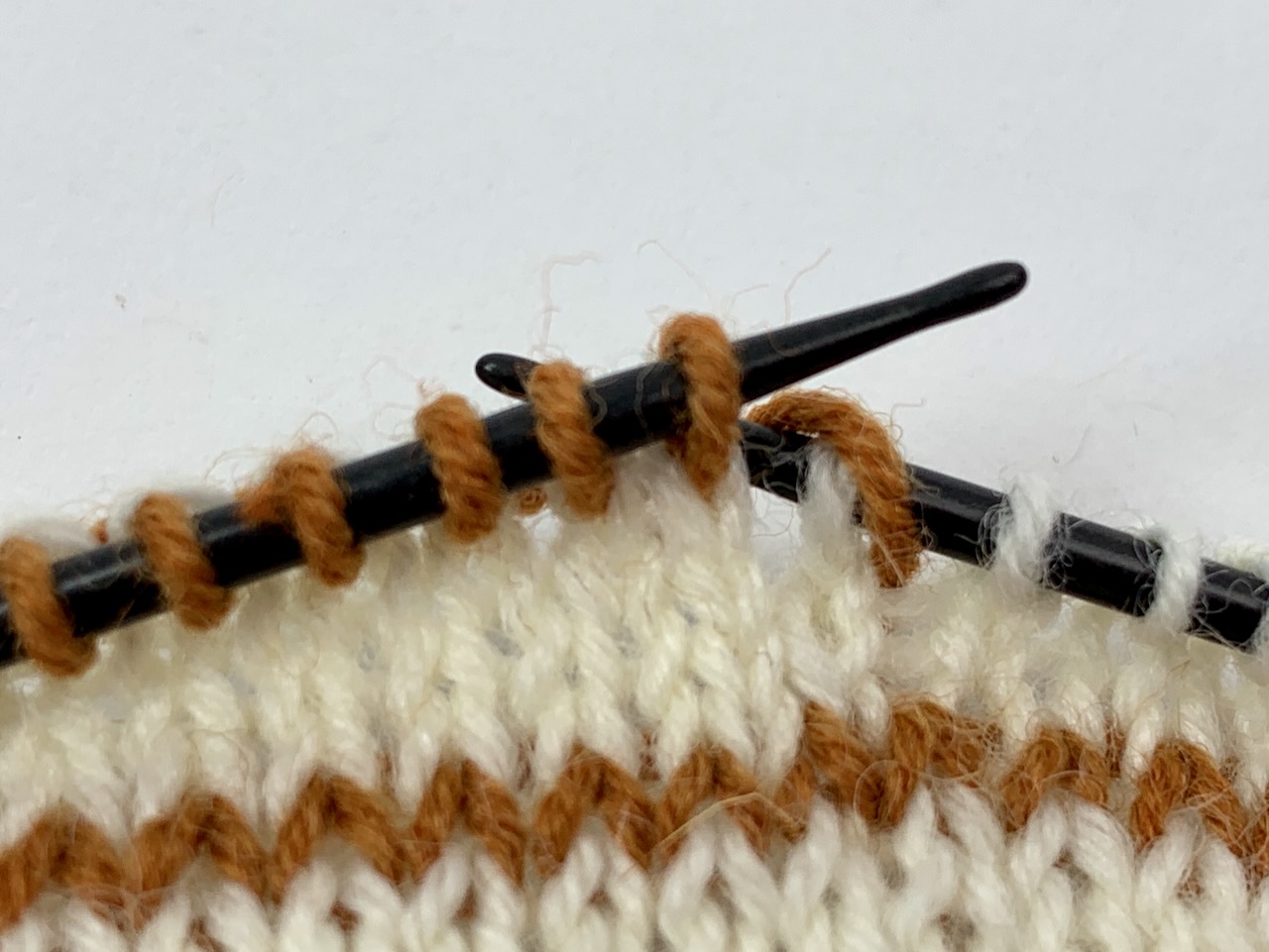 Der neue Faden liegt als Umschlag vor der letzten Masche mit der alten Farbe.