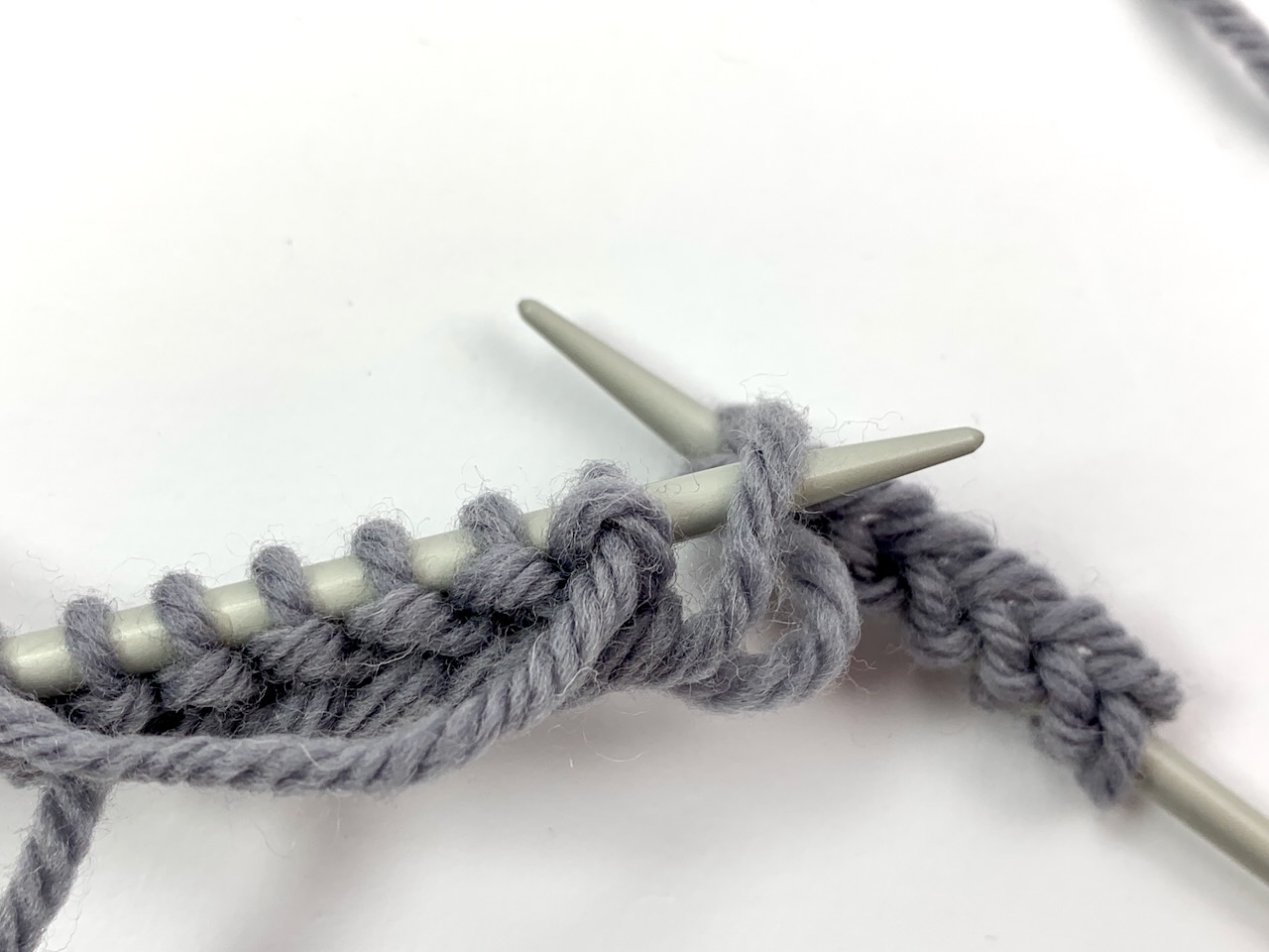 Masche gefallen im Maschenanschlag - vorderer Faden wird auf die linke Nadel geführt.