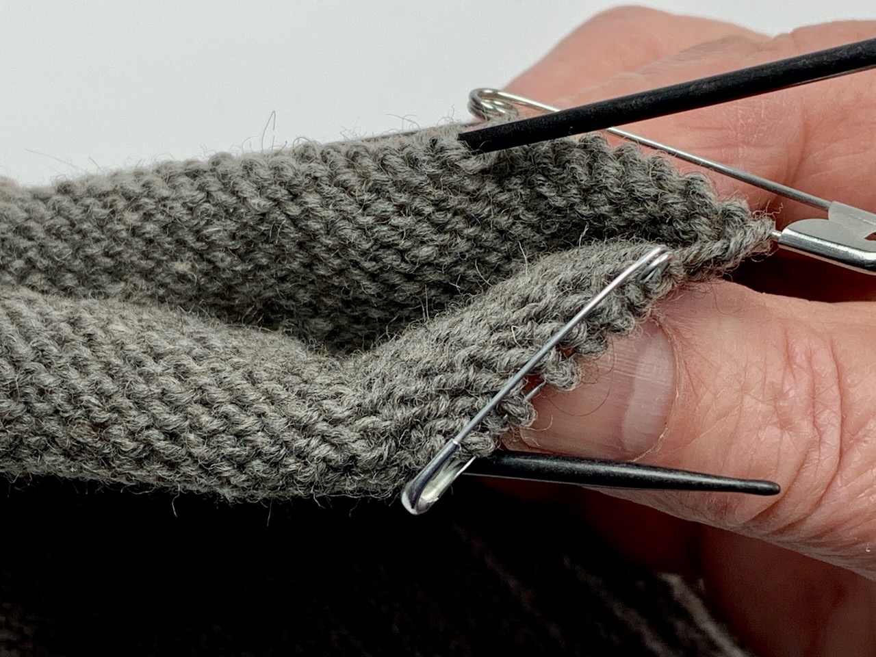 Daumenmaschen werden auf zwei Sicherheitsnadeln geparkt - Fäustling